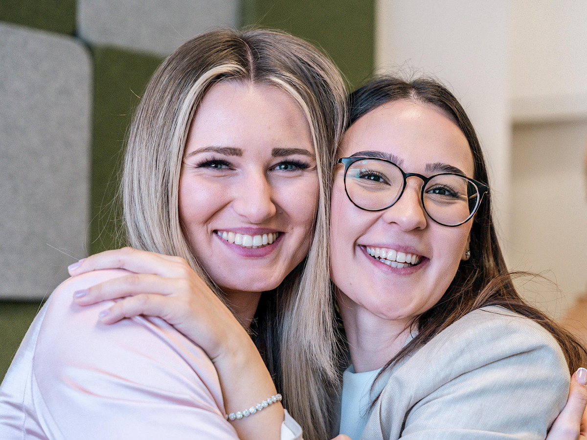 Zwei gut gelaunte junge Frauen stehen Schulter an Schulter zusammen