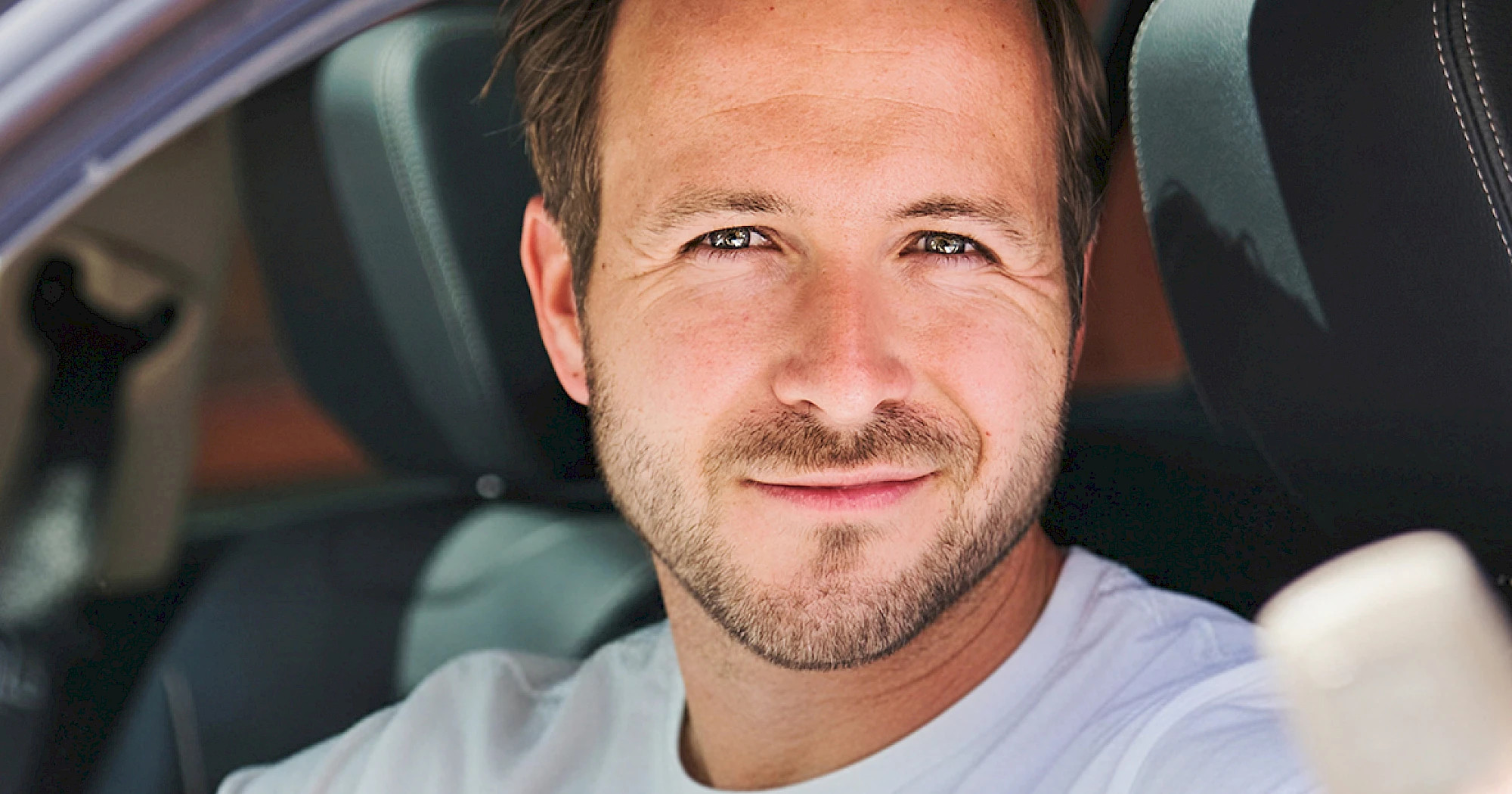 Mann sitzt in einem E-Auto und schaut aus dem Fenster