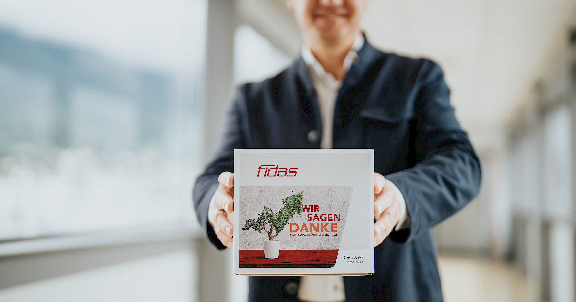 Mann hält ein Paket in die Kamera auf dem eine Wachstumsprognose für den Onlinehandel dargestellt wird.