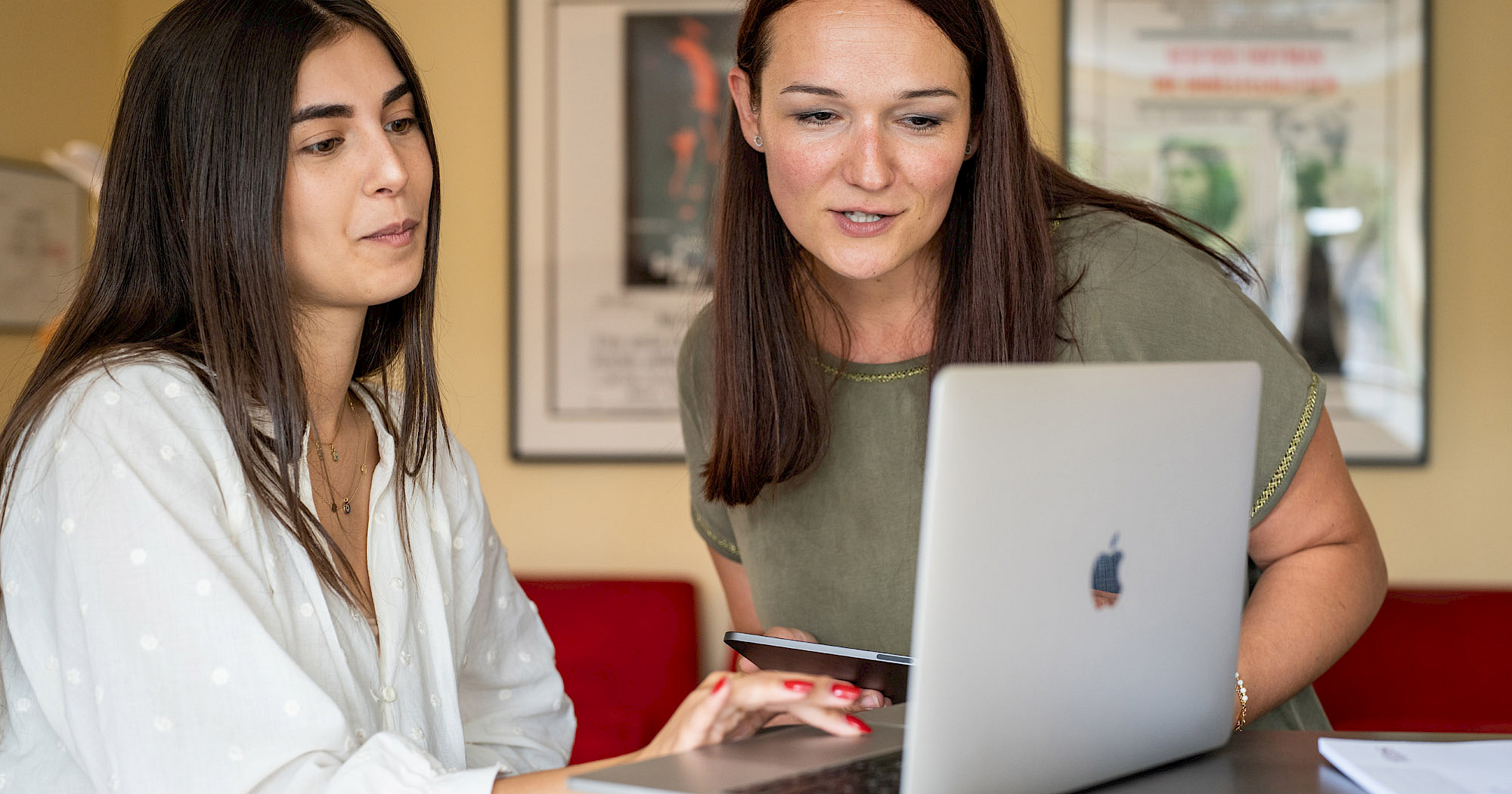 Zwei Frauen sitzen gemeinsam mit Laptop in Büro und diskutieren zu KI in der Steuerberatung.