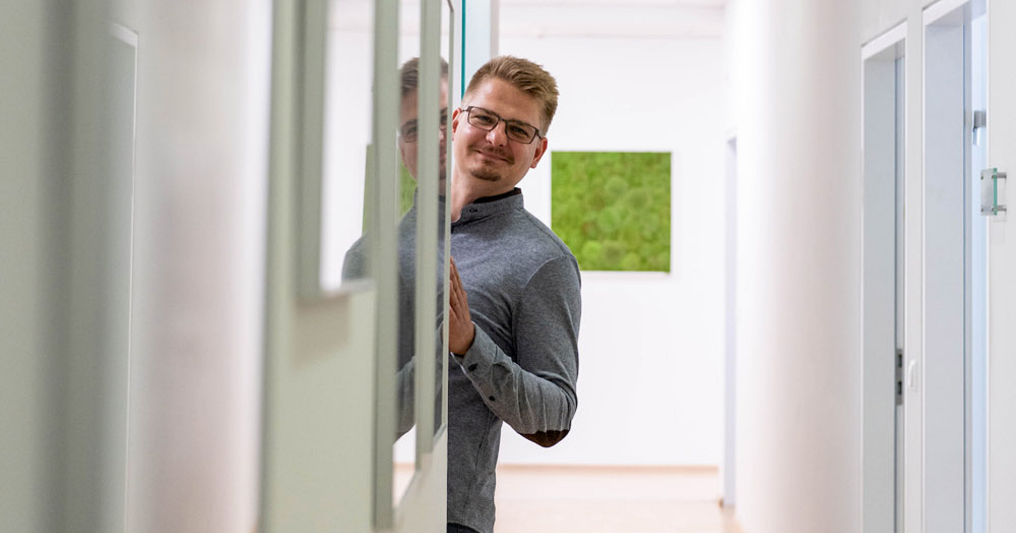 Mann schaut in Büro um die Ecke.