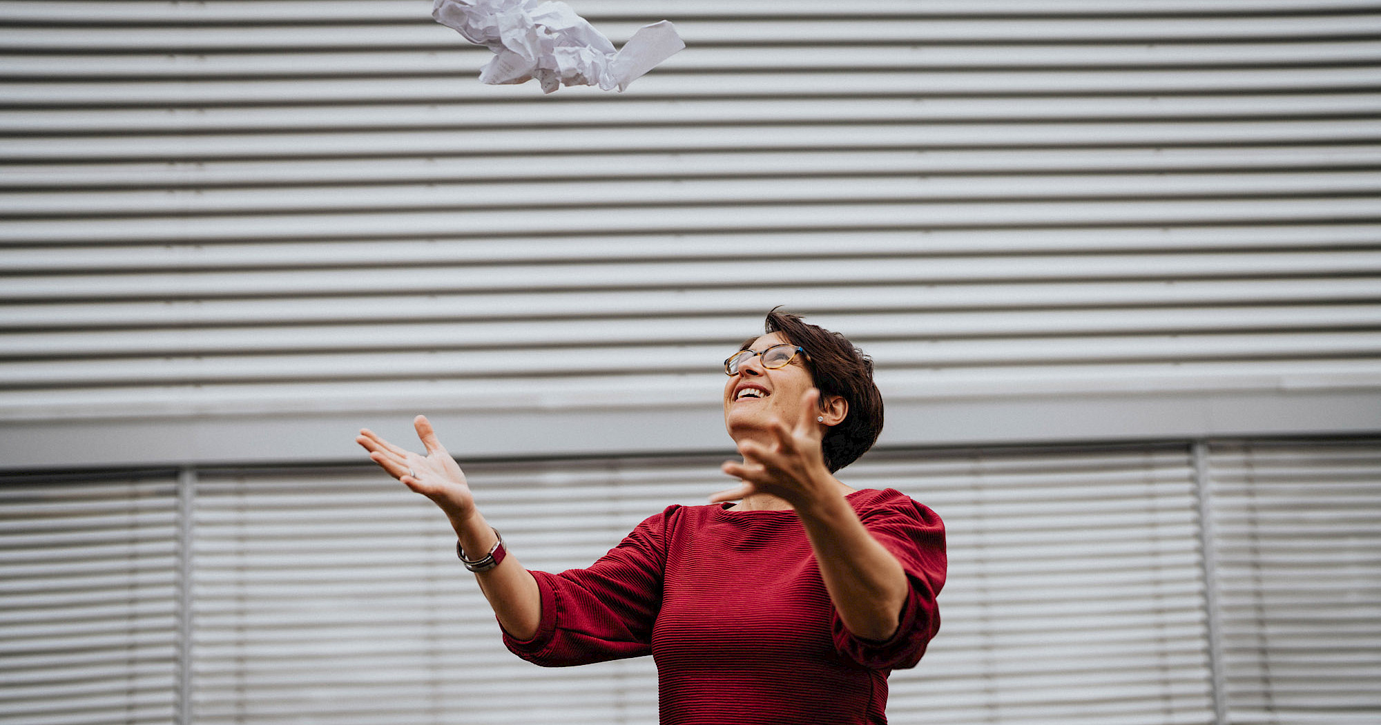 Frau schmeißt Papier in die Luft.