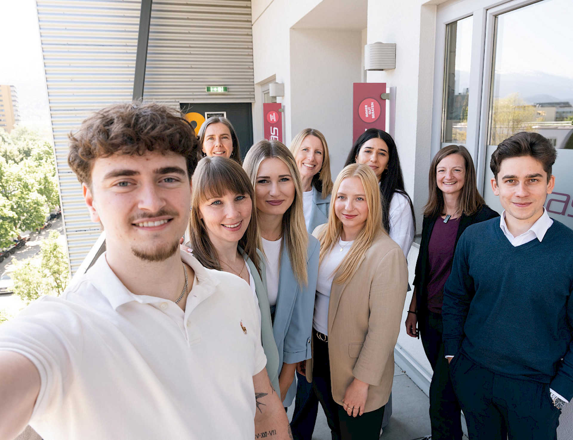 Mehrere weibliche und männliche Personen machen ein Selfie vor dem Büro in Innsbruck