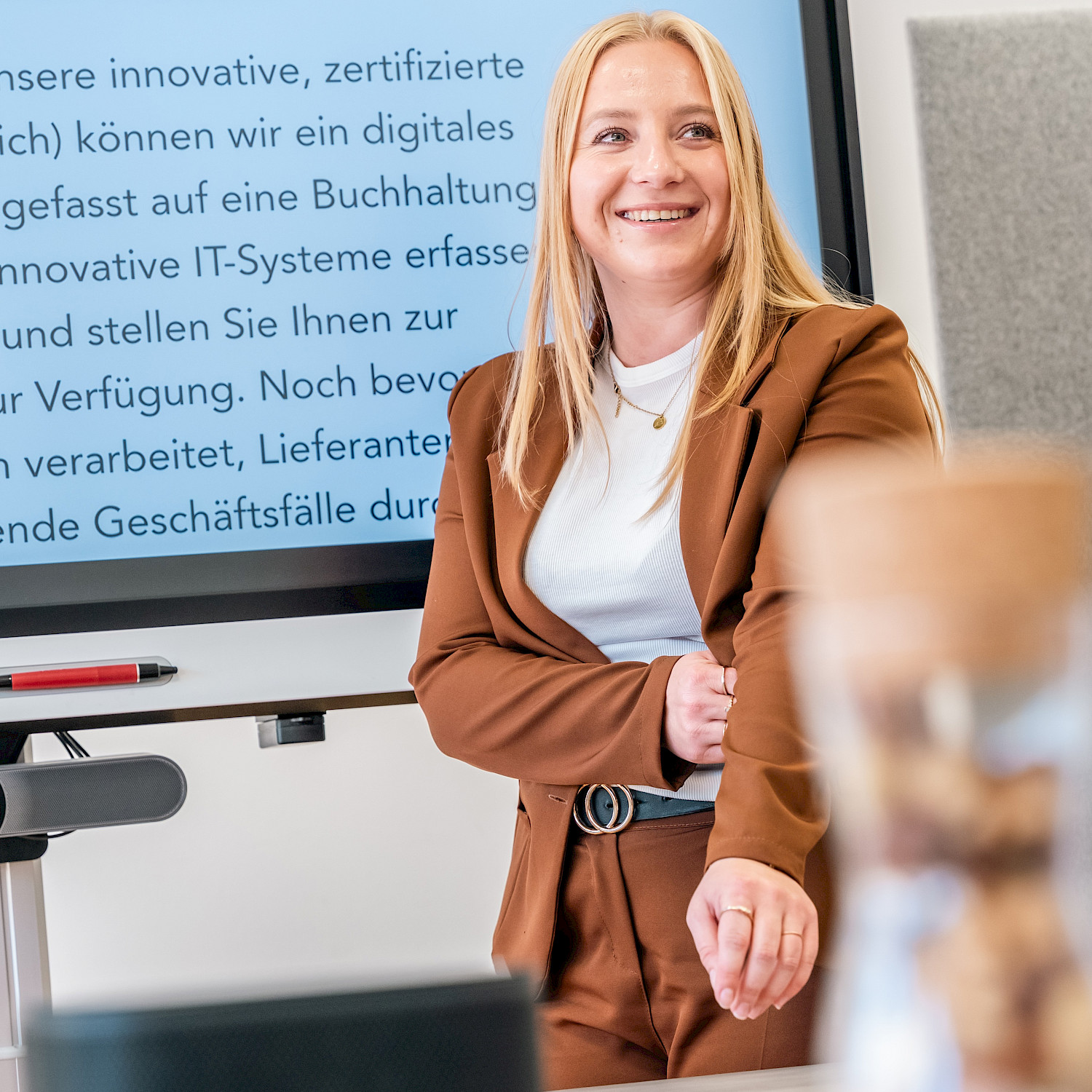 Eine junge Frau spricht über digitale Prozesse und steht vor einem Whiteboard.